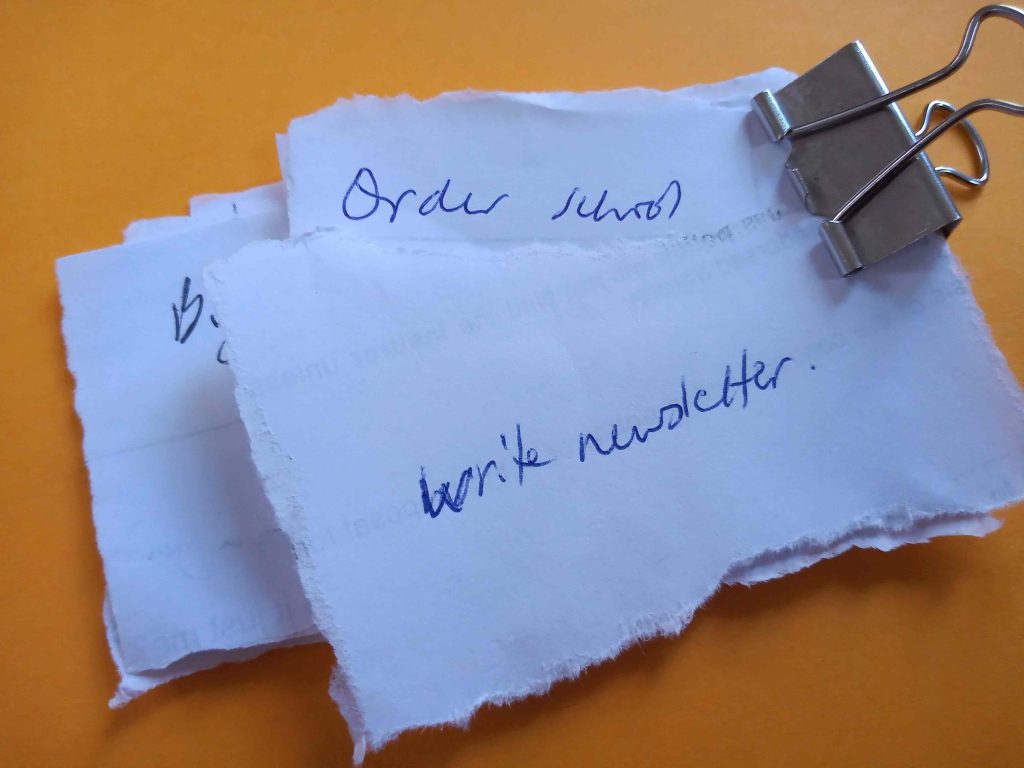 To-do tasks written on individual pieces of paper and clipped together.