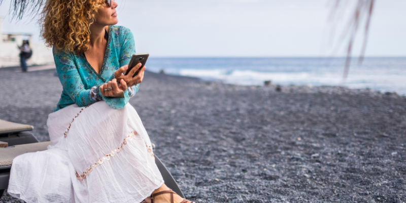 Woman sitting on a pebbly beach looking reflective, considering a job change.